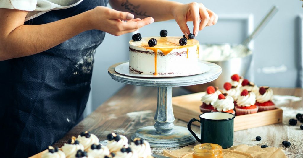 Mujer repostera decorando una torta dulce